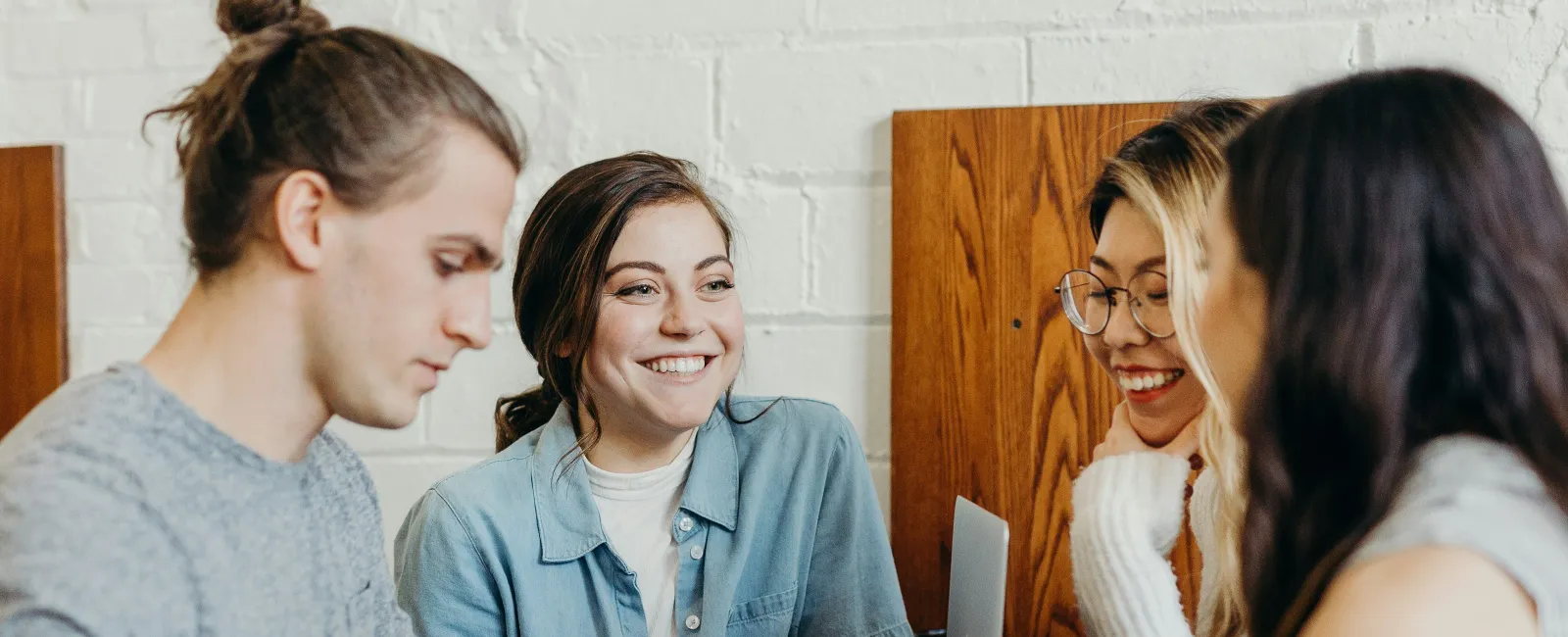 Group of young adults socializing and working together at a cafe with coffee and tablets.