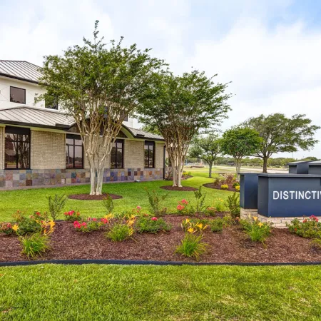 Exterior view of Distinctive Dental Services building with landscaped garden and signage under a cloudy sky.