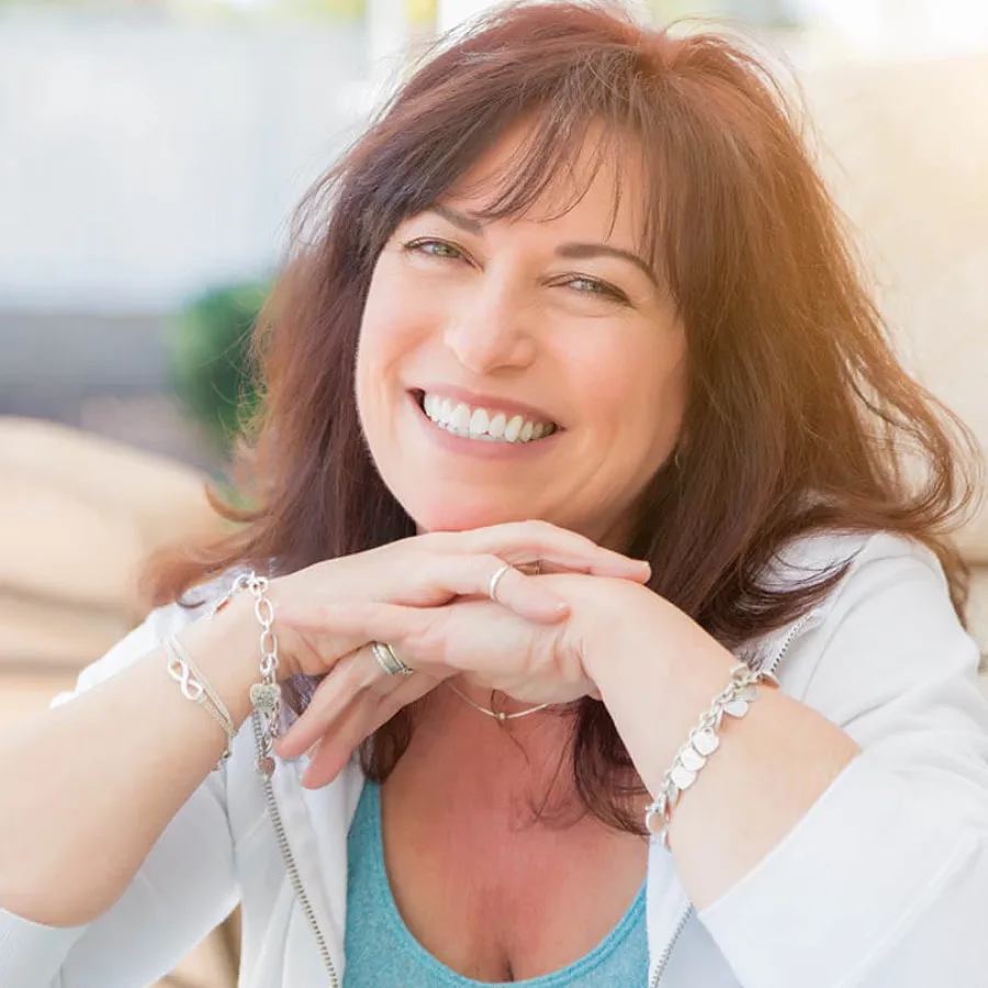 a woman smiling and holding her hands together